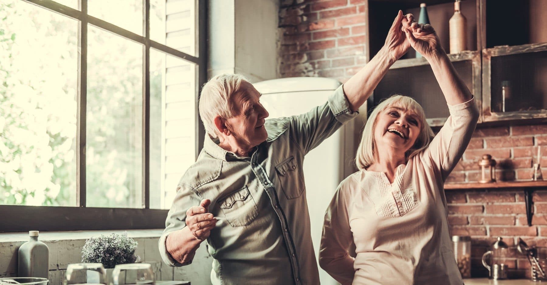Elderly couple celbrating with hands up in the air, smiling and looking at each other,